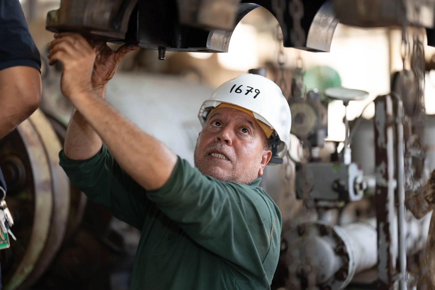 Industrial technician inspecting machinery while wearing a hard hat — illustrative photograph