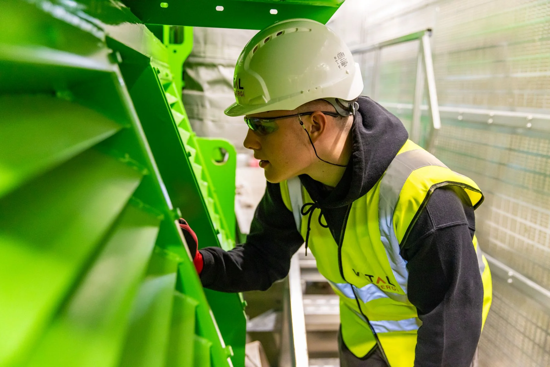 Worker in protective equipment inspecting industrial machinery — illustrative photograph