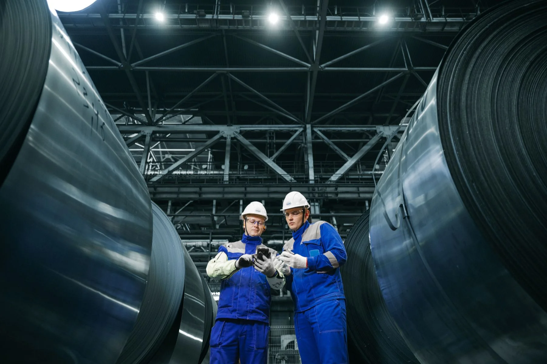 Industrial workers reviewing steel coils in a factory — illustrative photograph