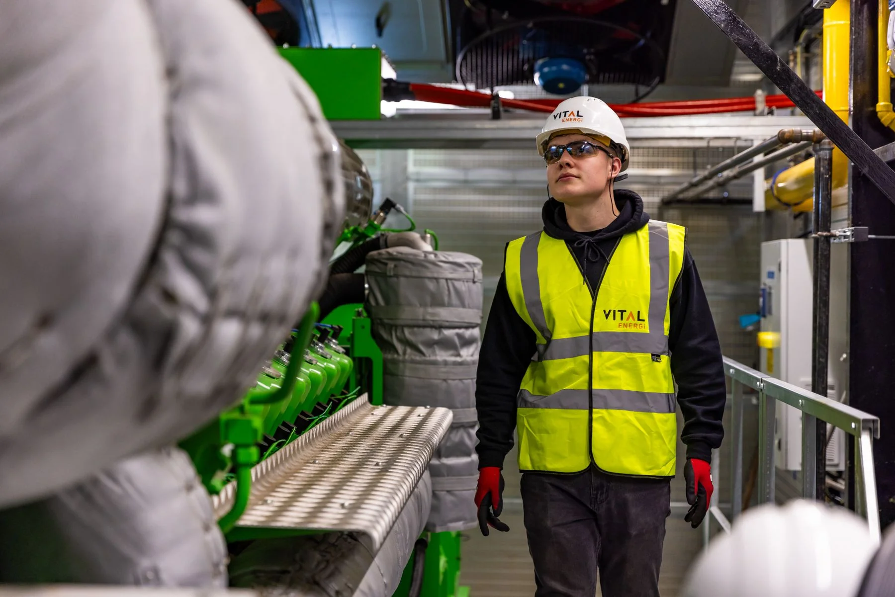 Worker wearing protective equipment reviewing an industrial workplace — illustrative photograph