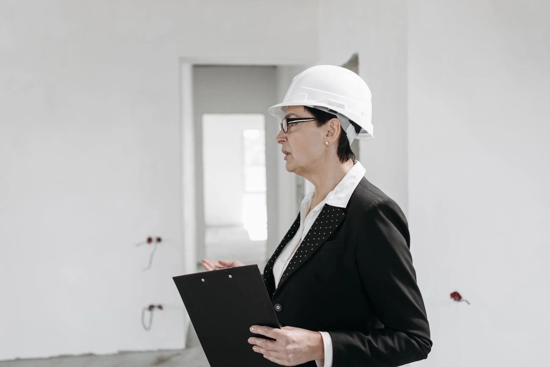 Engineer wearing a hard hat and holding a clipboard during a site review — illustrative photograph